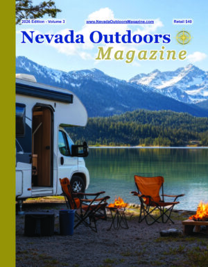 Cover of the 2026 Nevada Outdoors Magazine, Volume 3, featuring a recreational vehicle at a lakeside campsite with mountain scenery, camp chairs, and a campfire.